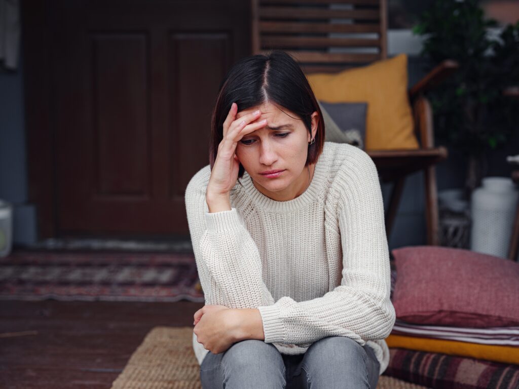 Young depressed asian woman sitting on porch of backyard.